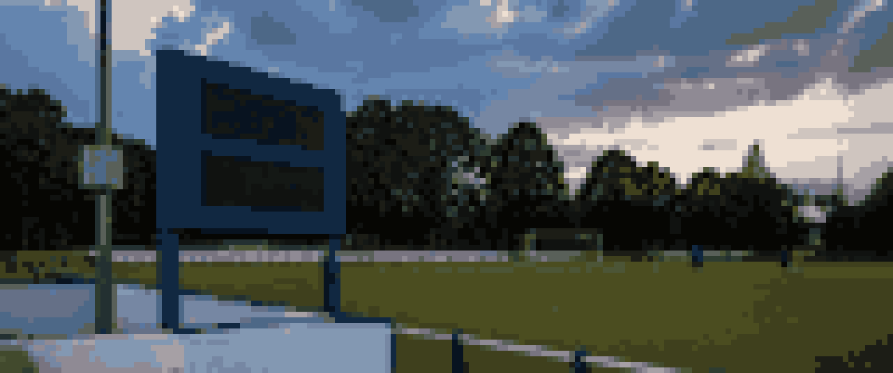 Pixelgrafik: eine Anzeigetafel am Rand eines kleinen Fussballplatzes im Abendlicht