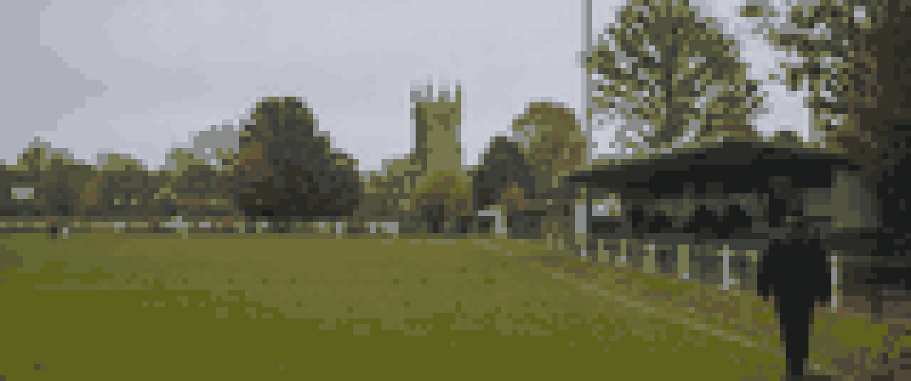 Pixelgrafik: ein kleiner Dorfsportplatz an einem grauen Herbsttag, eine niedrige Tribuene, Baeume dahinter